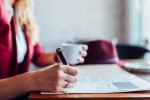 Closeup of business woman signing documents in a cafe