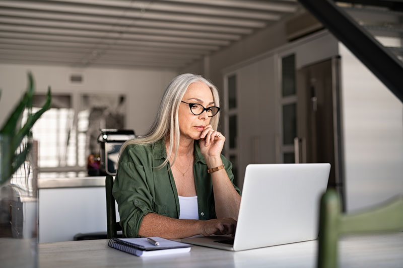 Woman working on laptop sitting at desk in her home