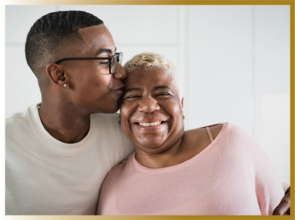 Young adult son kisses his middle aged mothers forehead