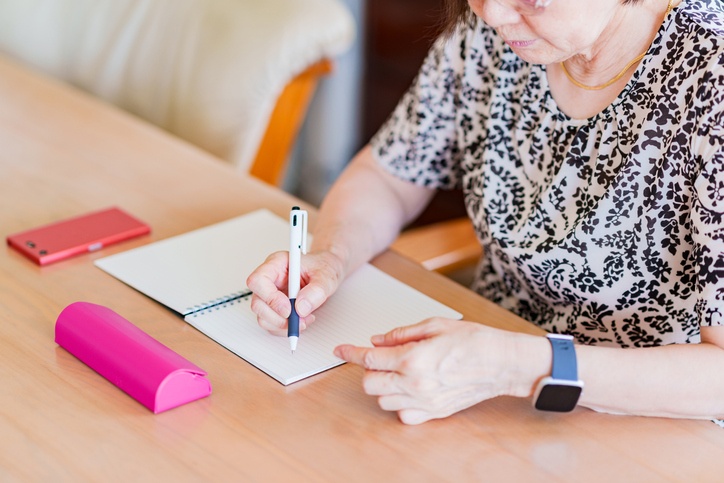 Estate planning for Alzheimer's concept: a senior woman writing a memo in a notebook