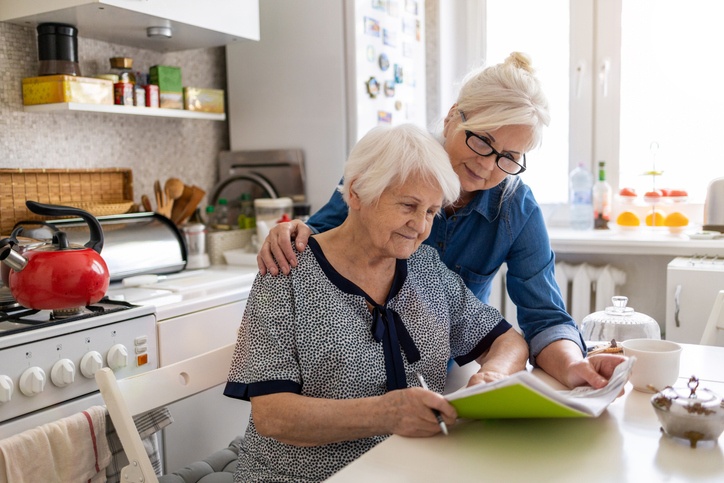 Estate planning for someone with Dementia concept: Mature woman helping elderly mother with paperwork